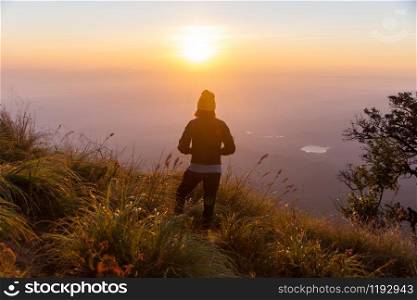 rear of happy woman stand on top mountain looking view with sunrise and mist at (Doi Norg Doi Luang National Park) Phayao province. soft focus.