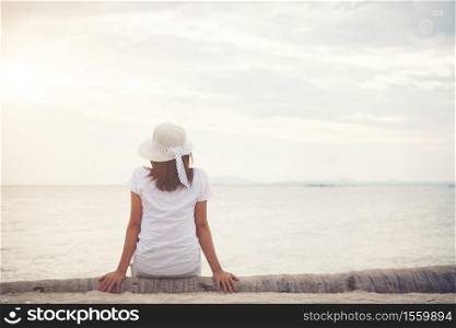 Rear of young woman sit on dead wood on the beach. Freedom enjoying holiday. Women lifestyle concept.