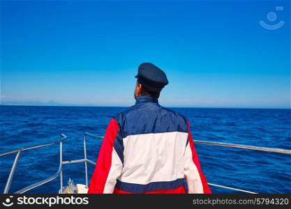 rear sailor man sailing sea ocean in a boat with captain cap looking horizon