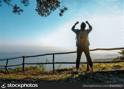 Rear view back of Young asian hiking man standing at view point and rise-up hands with happy on peak mountain, copy space