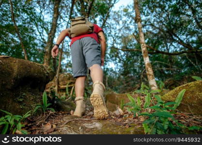 Rear view, back of young trekking man with backpack walking up the steep slope of the rocks, copy space