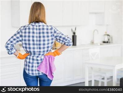 rear view female housekeeper orange gloves holding pink napkin kitchen