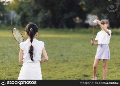 rear view girl playing badminton with her friend