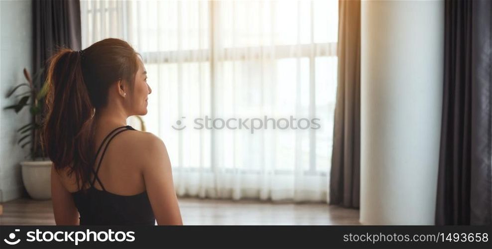 Rear view image of a beautiful young asian woman preparing to workout at home