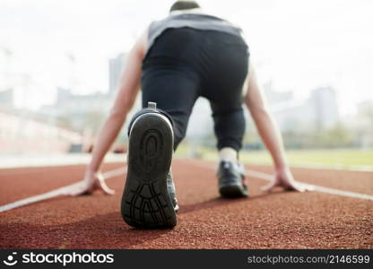 rear view male athlete taking position red race track