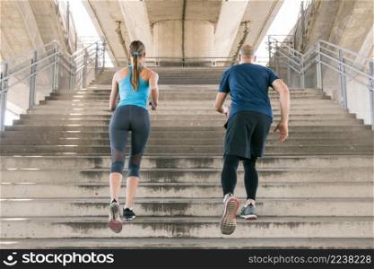 rear view male female athlete jogging staircase