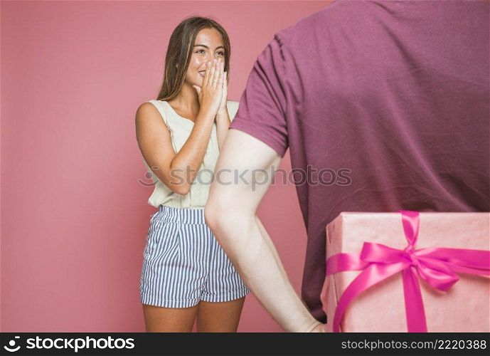 rear view man hiding gift box standing front surprised woman