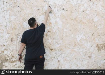 rear view man making graffiti peeled wall