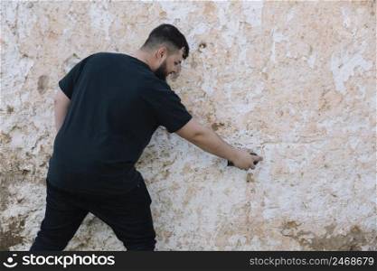 rear view man painting graffiti damaged wall