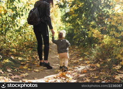 rear view mother daughter walking forest