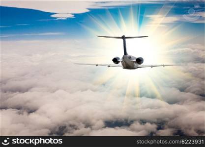 Rear view of a airplane that is flying high above the clouds. Flying an airplane in morning sun