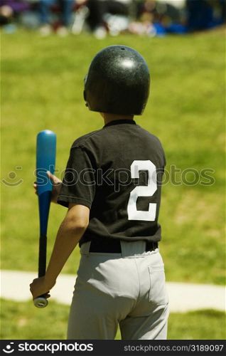 Rear view of a baseball player holding a baseball bat