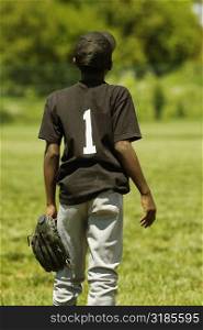 Rear view of a baseball player holding a baseball glove
