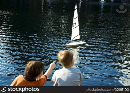 Rear view of a boy and a girl sitting beside a lake, New York City, New York State, USA
