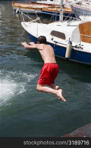 Rear view of a boy jumping in water, Borgo Marinaro, Bay of Naples, Naples, Naples Province, Campania, Italy