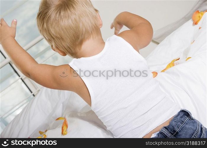 Rear view of a boy playing on the bed