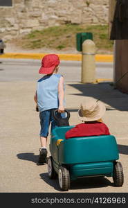 Rear view of a boy pulling a toy car with a baby on it, St. Augustine, Florida, USA