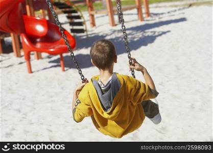 Rear view of a boy swinging on a chain swing ride