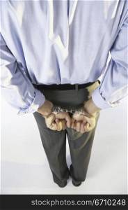 Rear view of a businessman&acute;s hands handcuffed behind his back