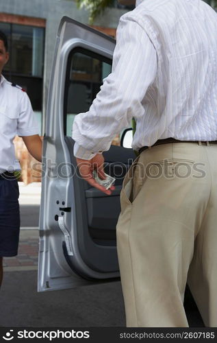 Rear view of a businessman giving tip to a waiter