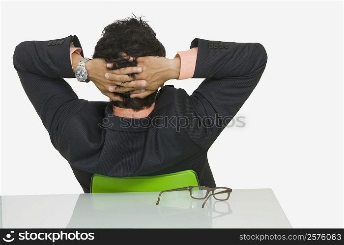 Rear view of a businessman sitting with his hands behind his head