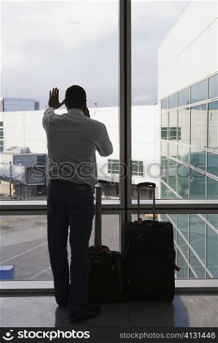 Rear view of a businessman standing with her luggage at an airport