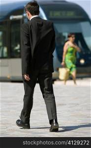 Rear view of a businessman walking on a sidewalk, Bordeaux, Aquitaine, France