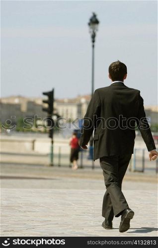 Rear view of a businessman walking on a sidewalk, Bordeaux, Aquitaine, France