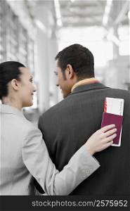 Rear view of a businesswoman and a businessman looking at each other at an airport