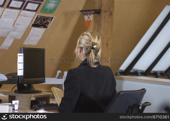 Rear view of a businesswoman sitting in front of a desktop PC