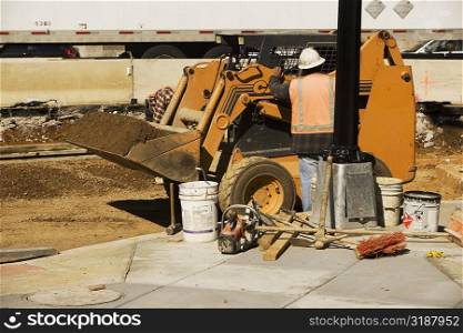 Rear view of a construction worker standing in front of an earth mover