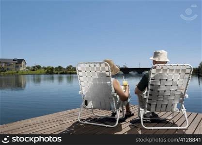 Rear view of a couple sitting on chairs at the boardwalk