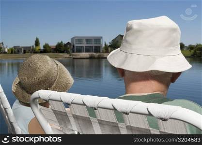 Rear view of a couple sitting on chairs at the lakeside