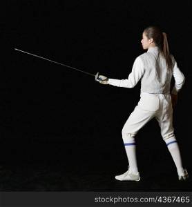 Rear view of a female fencer holding a fencing foil