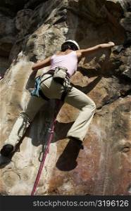 Rear view of a female rock climber scaling a rock face