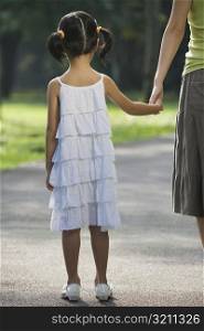 Rear view of a girl holding her mother&acute;s hand