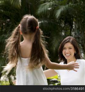 Rear view of a girl running to hug her mother in a park