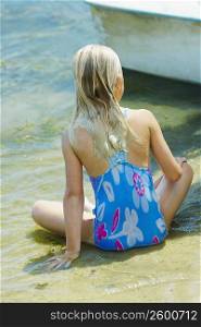 Rear view of a girl sitting at the lakeside