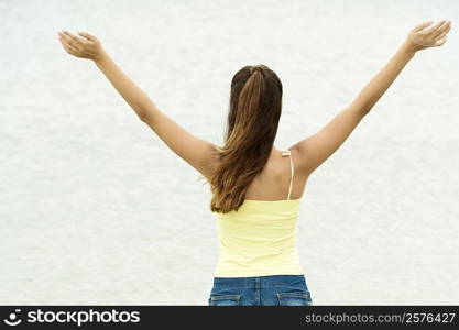 Rear view of a girl standing in water with her arms outstretched