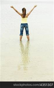 Rear view of a girl standing on the beach with her arms outstretched