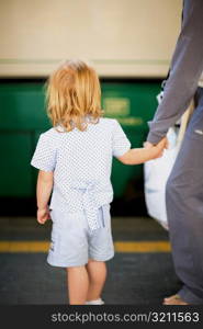 Rear view of a girl standing with her father at a railroad station platform, Rome, Italy