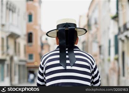 Rear view of a gondolier standing wearing a hat, Venice, Veneto, Italy