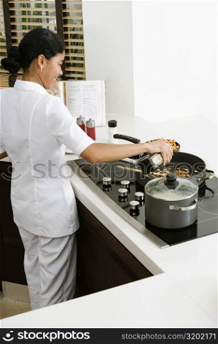 Rear view of a maid preparing food in the kitchen and smiling