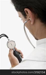 Rear view of a male doctor holding a blood pressure gauge