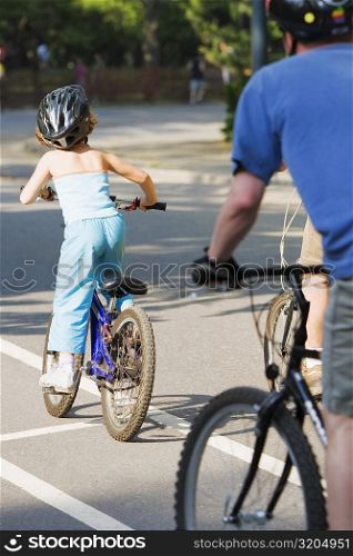 Rear view of a man and a girl cycling