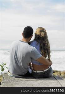 Rear view of a man and a woman sitting on the beach