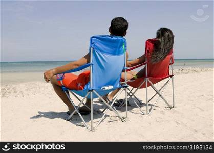 Rear view of a man and a woman sitting on the beach