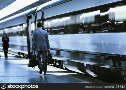 Rear view of a man and a woman walking at a railroad station, Rome, Italy