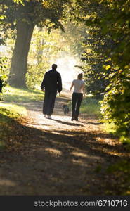 Rear view of a man and a woman walking on a dirt road in a park