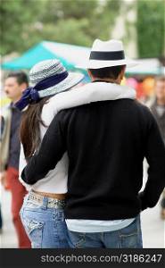 Rear view of a man and a woman with their arms around each other